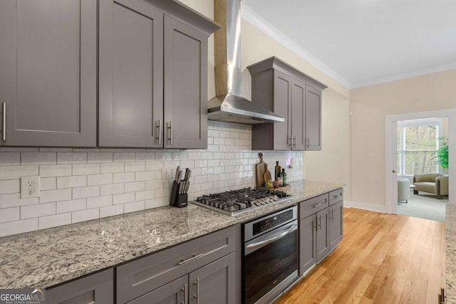 4457 Equity Ct, Ellenwood, GA 30294 - kitchen with stainless steel appliances, wall chimney range hood, gray cabinetry, crown molding, and light wood-style floors