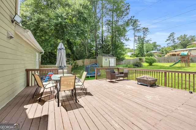 557 Spring Creek Way NE, Marietta, GA 30068 - wooden deck featuring outdoor dining area, a fire pit, and a playground