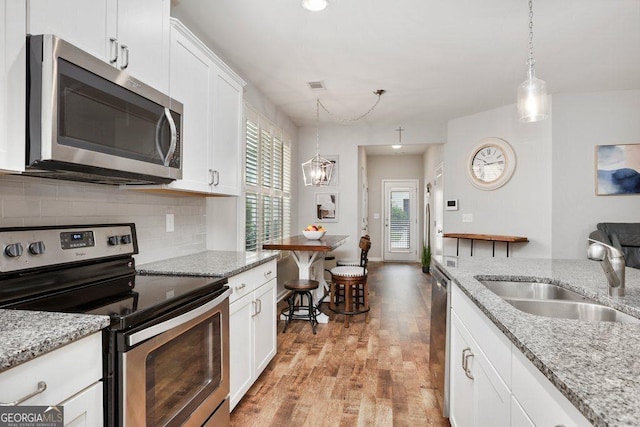 6115 Stella Light Dr, Flowery Branch, GA 30542 - kitchen with stainless steel appliances, a sink, light wood-type flooring, decorative backsplash, and white cabinets