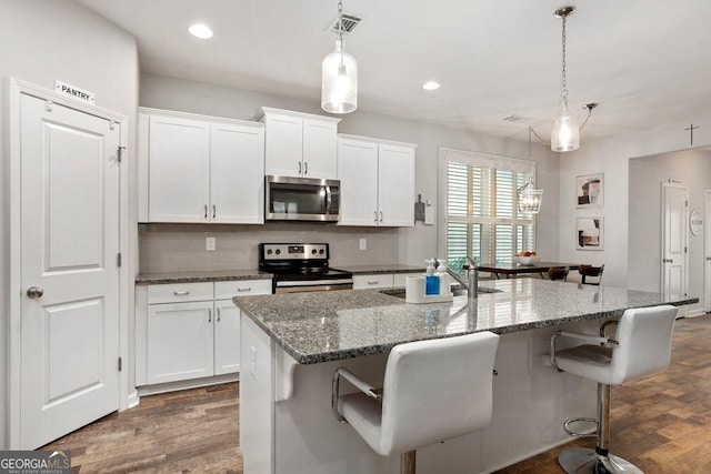 6115 Stella Light Dr, Flowery Branch, GA 30542 - kitchen with electric range oven, stainless steel microwave, white cabinets, a kitchen breakfast bar, and recessed lighting