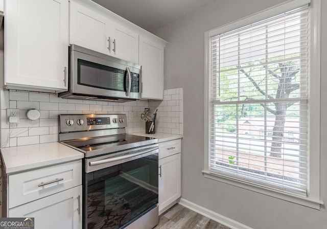 2038 Summertown Dr, Norcross, GA 30071 - kitchen featuring appliances with stainless steel finishes, decorative backsplash, light countertops, white cabinets, and light wood-style flooring