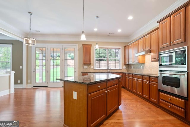 12194 Limeridge Ct, Alpharetta, GA 30004 - kitchen with stainless steel appliances, under cabinet range hood, a center island, light wood finished floors, and decorative backsplash