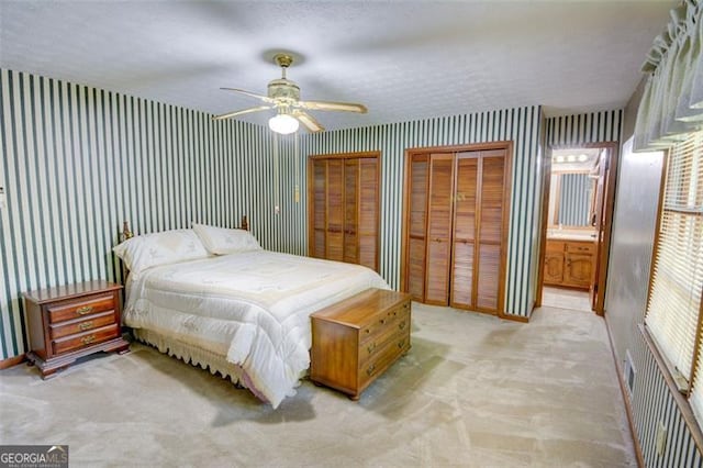 402 Princeton Way, Lawrenceville, GA 30044 - bedroom with wallpapered walls, light colored carpet, two closets, a ceiling fan, and ensuite bath