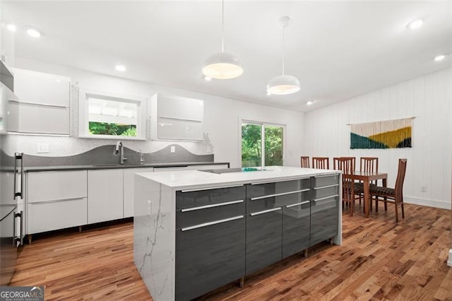 1492 Sagewood Cir, Stone Mountain, GA 30083 - kitchen with modern cabinets, light wood-style flooring, white cabinets, hanging light fixtures, and a kitchen island