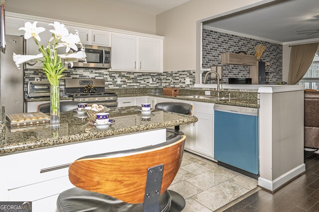 3343 Lathenview Ct, Milton, GA 30004 - kitchen with stainless steel appliances, a peninsula, white cabinets, decorative backsplash, and dark stone countertops
