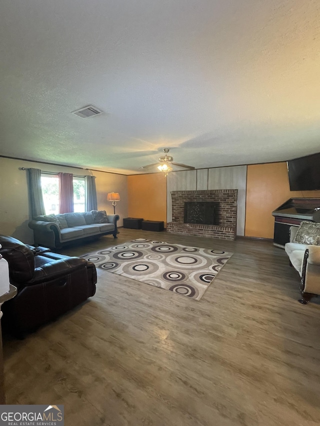 1191 Zoar Rd, Baxley, GA 31513 - living room with ceiling fan, wood finished floors, a brick fireplace, and a textured ceiling