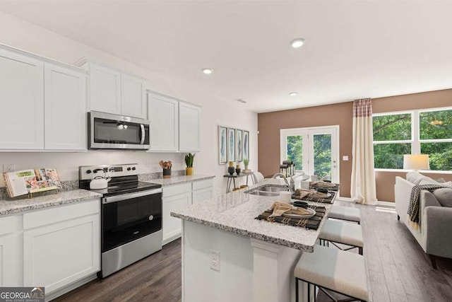 1404 Gray Branch Dr, Lawrenceville, GA 30045 - kitchen with appliances with stainless steel finishes, a sink, a breakfast bar area, white cabinetry, and dark wood-style flooring