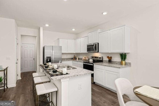 1404 Gray Branch Dr, Lawrenceville, GA 30045 - kitchen featuring appliances with stainless steel finishes, a sink, white cabinetry, a breakfast bar area, and recessed lighting