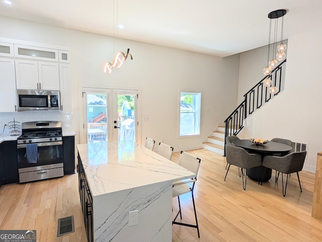123 Dahlgren St SE, Atlanta, GA 30317 - kitchen with appliances with stainless steel finishes, light wood-type flooring, light stone counters, a center island, and pendant lighting