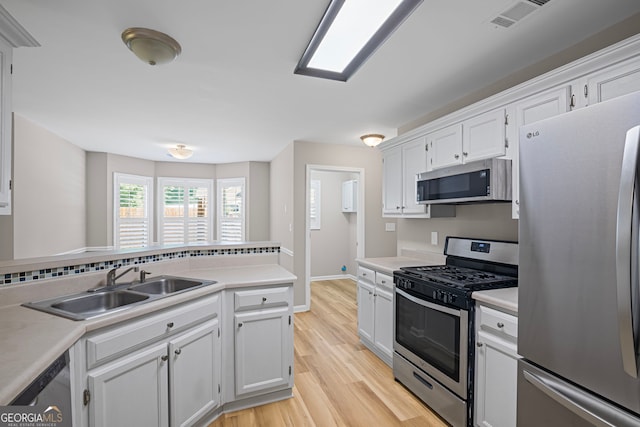 105 Paces Landing Trl, Newnan, GA 30263 - kitchen featuring stainless steel appliances, a sink, light countertops, light wood finished floors, and white cabinetry