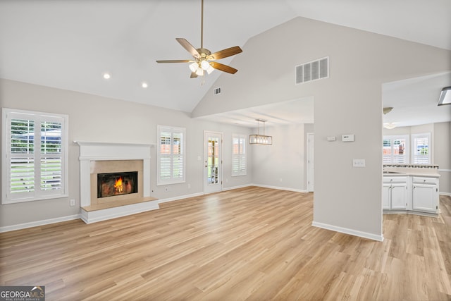 105 Paces Landing Trl, Newnan, GA 30263 - unfurnished living room featuring a ceiling fan, a glass covered fireplace, light wood-style floors, plenty of natural light, and high vaulted ceiling