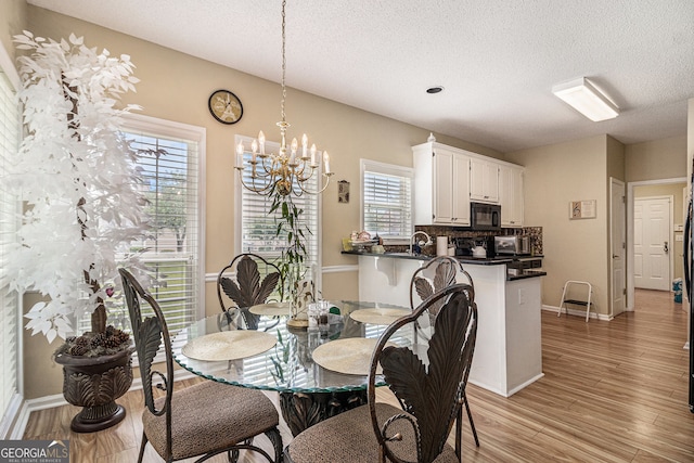 2928 Mandy Ct, Jonesboro, GA 30236 - dining space featuring a textured ceiling, a chandelier, light wood finished floors, and baseboards