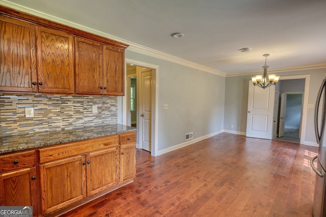 1177 Castle Way, Norcross, GA 30093 - kitchen with a chandelier, brown cabinetry, backsplash, baseboards, and ornamental molding