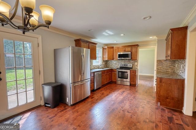 1177 Castle Way, Norcross, GA 30093 - kitchen featuring appliances with stainless steel finishes, crown molding, brown cabinetry, a chandelier, and decorative backsplash