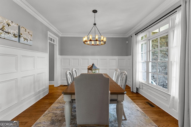 55 Jolie Ln, Sharpsburg, GA 30277 - dining area featuring a chandelier, healthy amount of natural light, a decorative wall, crown molding, and wainscoting