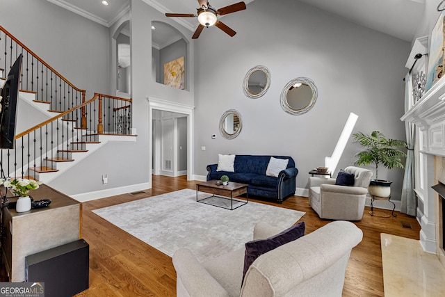 55 Jolie Ln, Sharpsburg, GA 30277 - living room featuring ceiling fan, a fireplace, a towering ceiling, stairway, and crown molding
