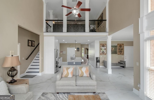 413 Canterbury Way, Jonesboro, GA 30236 - living area featuring a high ceiling, light marble finish flooring, a ceiling fan, decorative columns, and stairs