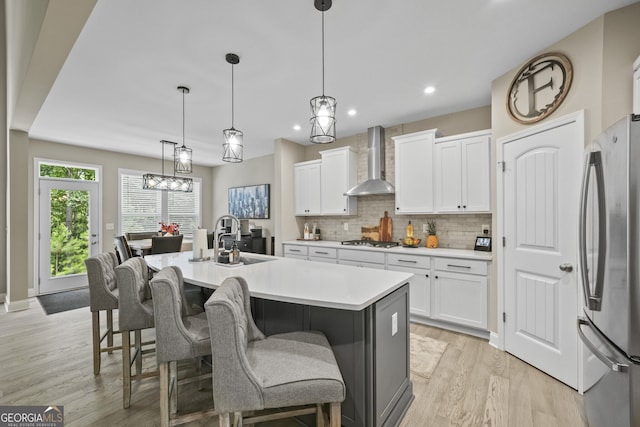 2118 Harmony Dr, Canton, GA 30115 - kitchen with wall chimney exhaust hood, appliances with stainless steel finishes, decorative backsplash, light wood-type flooring, and white cabinetry