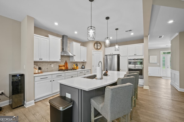 2118 Harmony Dr, Canton, GA 30115 - kitchen featuring stainless steel appliances, beverage cooler, wall chimney range hood, decorative backsplash, and white cabinets