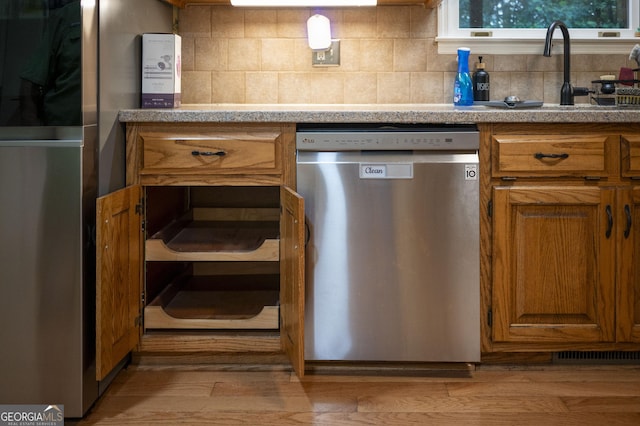 323 Mccartan Trl, Clarkesville, GA 30523 - kitchen with stainless steel appliances, brown cabinets, decorative backsplash, a sink, and wood finished floors