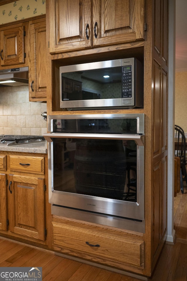 323 Mccartan Trl, Clarkesville, GA 30523 - kitchen with appliances with stainless steel finishes, under cabinet range hood, brown cabinets, and light countertops