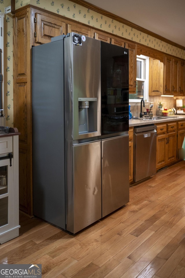 323 Mccartan Trl, Clarkesville, GA 30523 - kitchen with appliances with stainless steel finishes, brown cabinetry, light wood-style floors, ornamental molding, and a sink