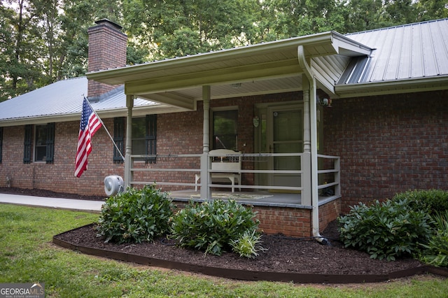 323 Mccartan Trl, Clarkesville, GA 30523 - view of exterior entry with brick siding, metal roof, a porch, and a chimney