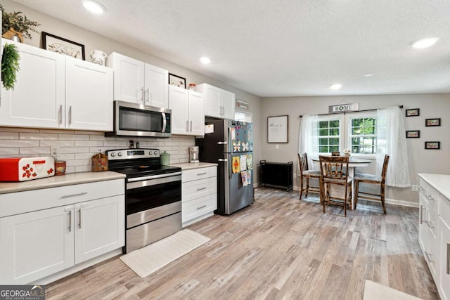 187 Angers Ct, Dahlonega, GA 30533 - kitchen with appliances with stainless steel finishes, light countertops, white cabinets, a textured ceiling, and light wood-type flooring