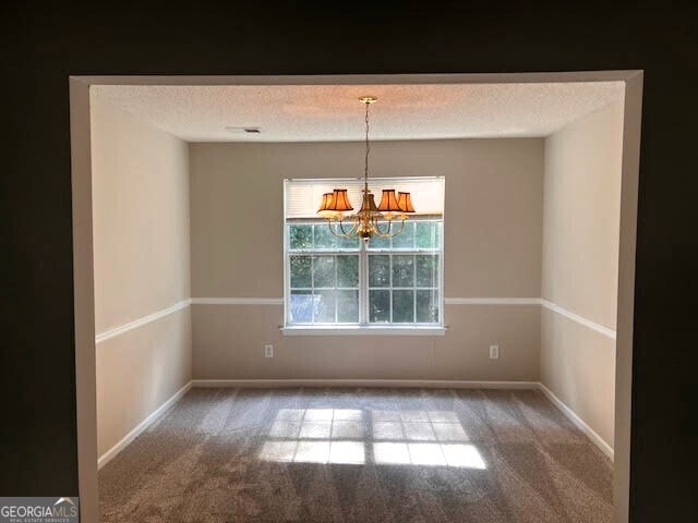 149 Titan Rd, Stockbridge, GA 30281 - unfurnished dining area with carpet flooring, a chandelier, a textured ceiling, and baseboards
