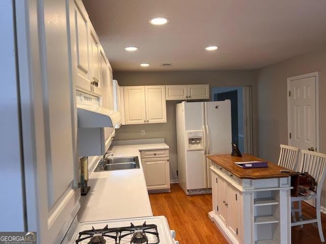 149 Titan Rd, Stockbridge, GA 30281 - kitchen with white appliances, ventilation hood, a sink, light wood finished floors, and white cabinets
