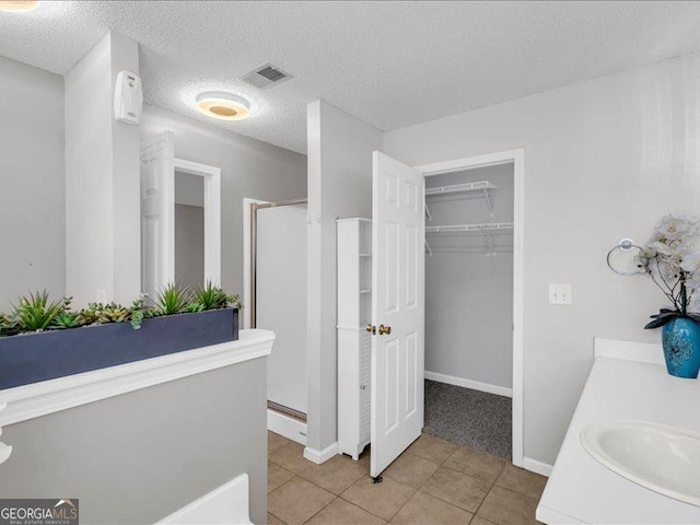 4517 Baker Grove Rd NW, Acworth, GA 30101 - full bath featuring a shower stall, tile patterned flooring, a walk in closet, vanity, and a textured ceiling