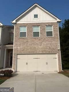 7695 Baron Rd, Fairburn, GA 30213 - view of front facade featuring driveway, board and batten siding, an attached garage, and brick siding