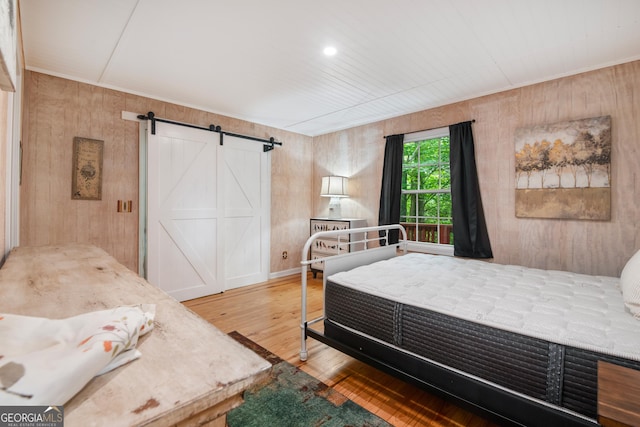 254 Rue Ln, Clayton, GA 30525 - bedroom with a barn door, wood finished floors, and wooden walls