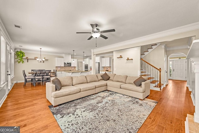 86 Crestview Dr, Guyton, GA 31312 - living room featuring stairs, crown molding, a ceiling fan, arched walkways, and light wood-style flooring