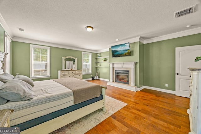 86 Crestview Dr, Guyton, GA 31312 - bedroom with crown molding, a glass covered fireplace, a textured ceiling, multiple windows, and wood finished floors
