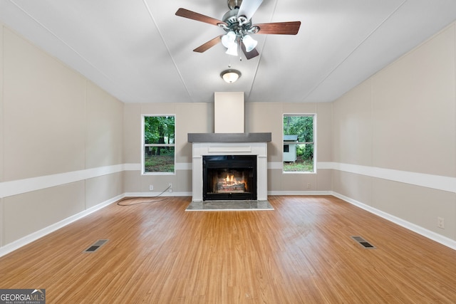 368 Hemlock Ln, Locust Grove, GA 30248 - unfurnished living room featuring a warm lit fireplace, wood finished floors, healthy amount of natural light, lofted ceiling, and ceiling fan