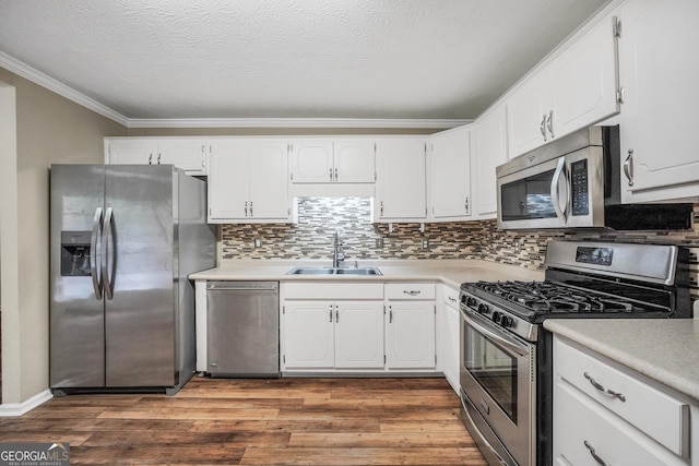 602 Pine Knoll Ct, Mcdonough, GA 30252 - kitchen featuring stainless steel appliances, a sink, ornamental molding, wood finished floors, and white cabinetry