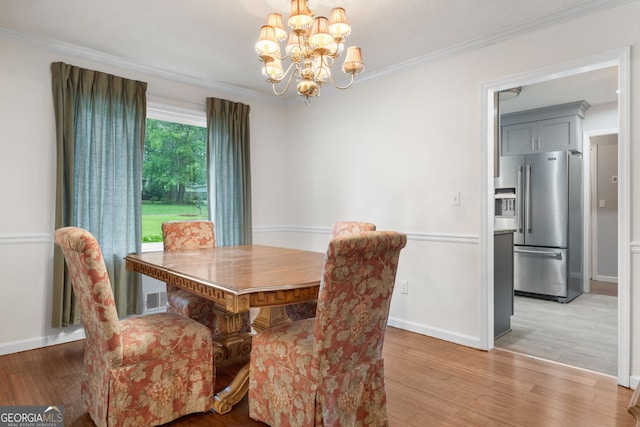 7972 Woods Ln, Jonesboro, GA 30236 - dining room featuring a chandelier, light wood-style floors, crown molding, and baseboards