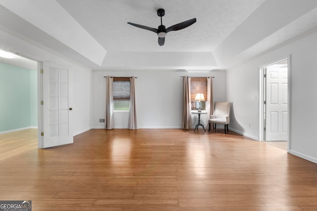 7972 Woods Ln, Jonesboro, GA 30236 - unfurnished room featuring a tray ceiling, ceiling fan, light wood-style floors, and baseboards