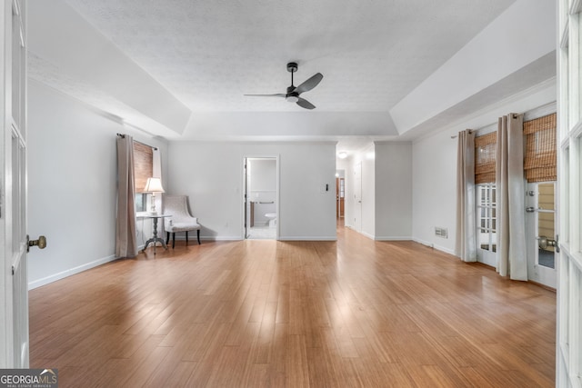 7972 Woods Ln, Jonesboro, GA 30236 - living room with ceiling fan, a tray ceiling, baseboards, and light wood-style flooring