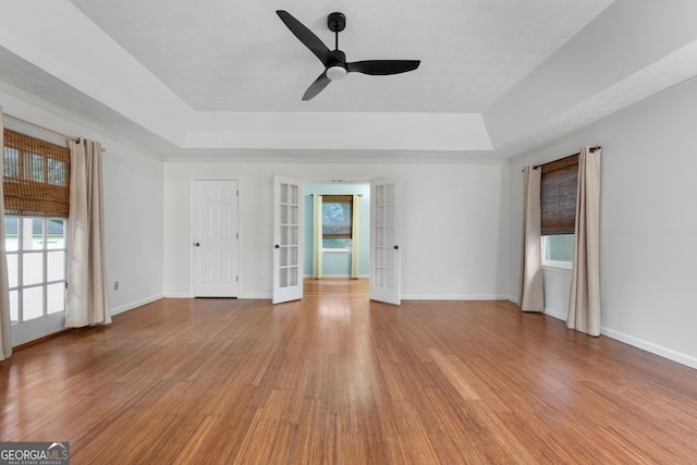 7972 Woods Ln, Jonesboro, GA 30236 - empty room featuring a tray ceiling, french doors, light wood finished floors, and ceiling fan