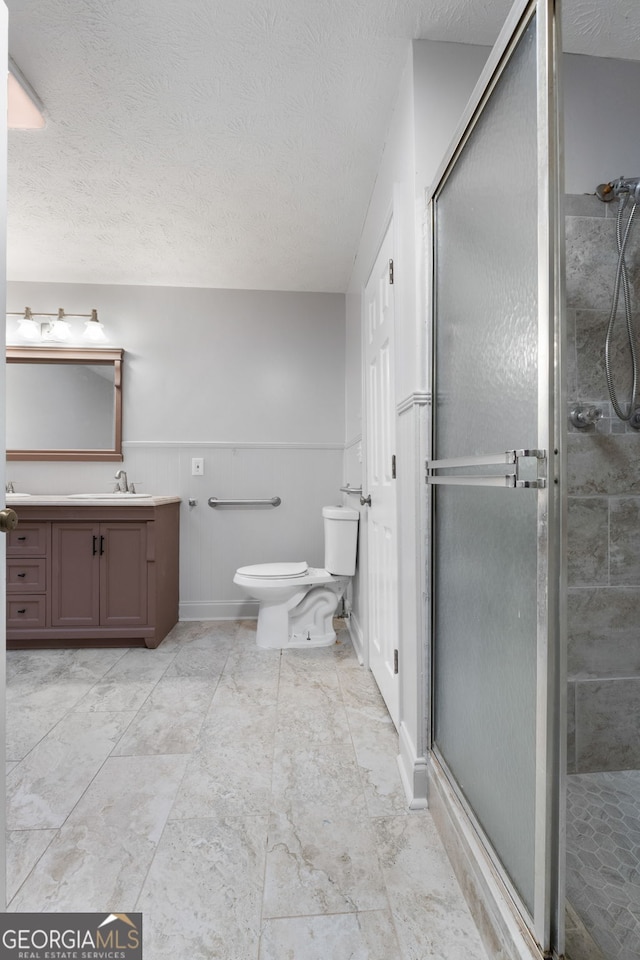 7972 Woods Ln, Jonesboro, GA 30236 - full bathroom with vanity, toilet, a stall shower, a textured ceiling, and wainscoting