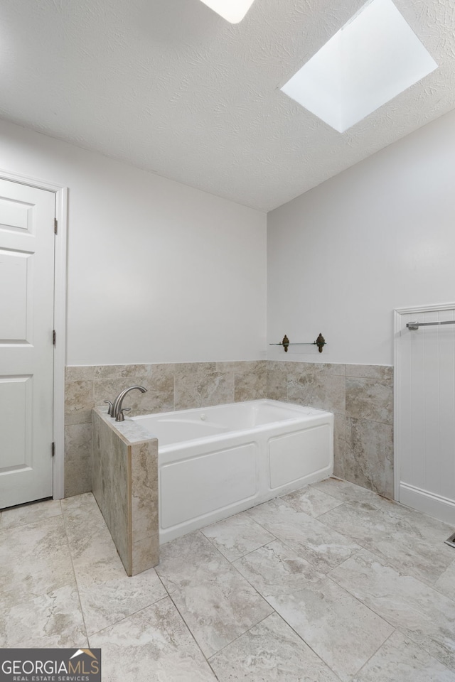 7972 Woods Ln, Jonesboro, GA 30236 - full bathroom featuring a bath, a wainscoted wall, a skylight, and a textured ceiling
