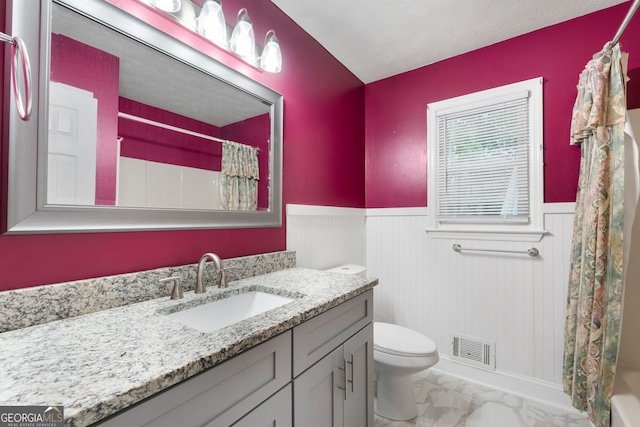 7972 Woods Ln, Jonesboro, GA 30236 - full bath with marble look tile flooring, wainscoting, vanity, toilet, and shower / bathtub combination with curtain