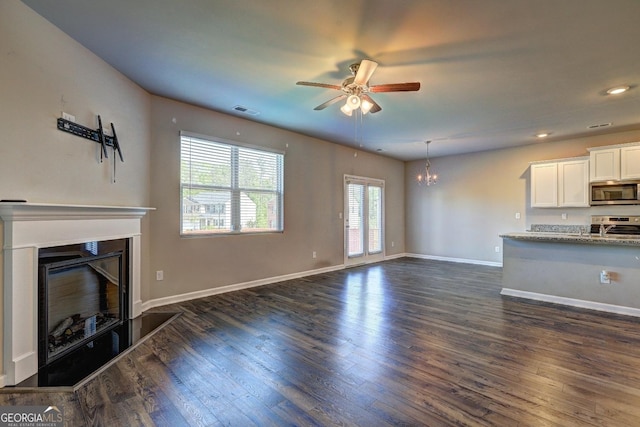 237 Cranapple Ln, Mcdonough, GA 30253 - unfurnished living room with a ceiling fan, a glass covered fireplace, a chandelier, dark wood-style flooring, and baseboards