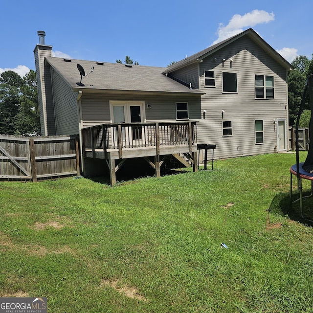 1649 Deer Creek Ln, Monroe, GA 30655 - back of house featuring a trampoline, a deck, a chimney, and a shingled roof