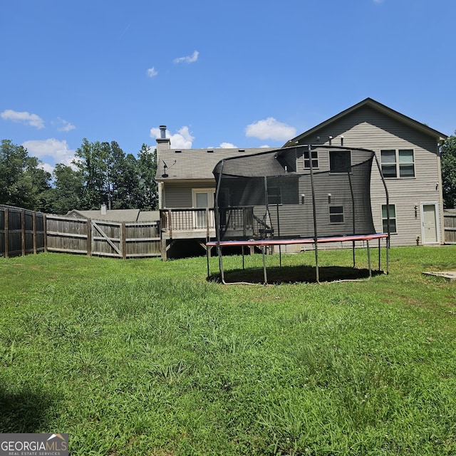 1649 Deer Creek Ln, Monroe, GA 30655 - rear view of property featuring a trampoline, a fenced backyard, and a chimney