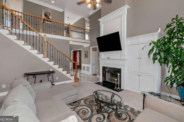 5810 Old Mill Trce, Lithonia, GA 30038 - living room featuring a ceiling fan, stairway, a fireplace with flush hearth, a high ceiling, and crown molding