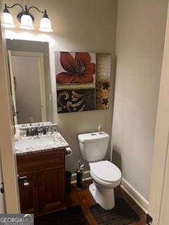 2594 Lassiter Rd, Forsyth, GA 31029 - half bath featuring vanity, toilet, wood finished floors, and baseboards