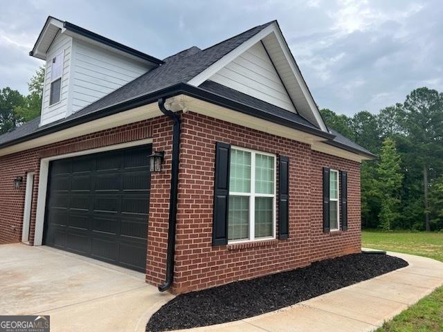 2594 Lassiter Rd, Forsyth, GA 31029 - view of side of property featuring brick siding, driveway, and an attached garage